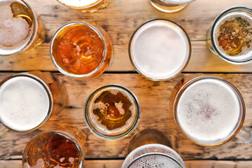Glassware with fresh beer on wooden background, top view