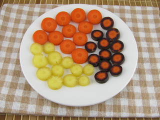 Geschnittene frische bunte Möhrenstücke auf einem Teller