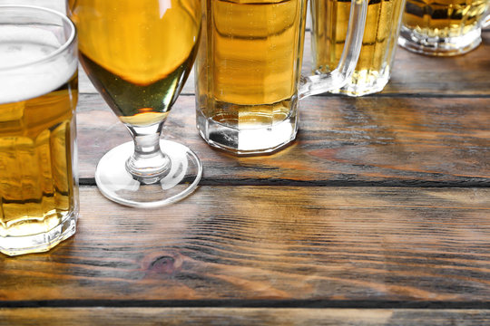 Glassware with fresh beer on wooden background