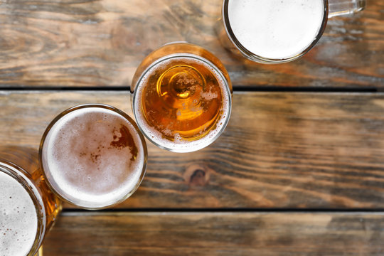 Glassware with fresh beer on wooden background, top view
