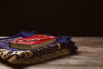 Holy book of Muslims, prayer beads and rug on wooden table