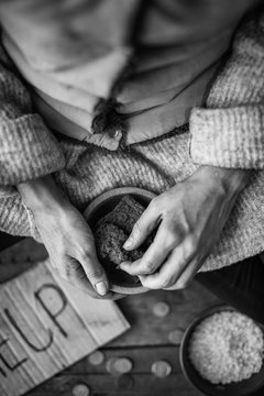 Poor woman holding bowl with some bread, focus on hands. Black and white effect