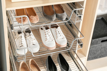 Different shoes on shelves of wardrobe closet