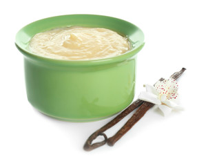 Tasty vanilla pudding in ramekin and sticks with flower on white background