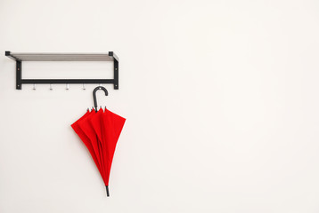 Stylish red umbrella hanging on wall