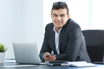 Young man in office wear working with laptop at table