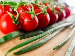 Little branch of cherry tomatoes and green onion leaves over wooden background.