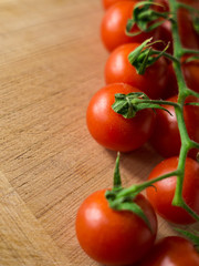 Little branch of cherry tomatoes over wooden background.