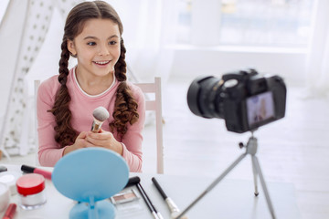 Best review. Pleasant pre-teen girl sitting at the table and reviewing makeup brushes while filming...