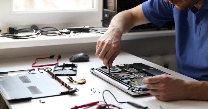 computer repair service - technician repairing broken laptop in office