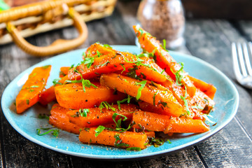 Carrots with spices and greens on a turquoise plate