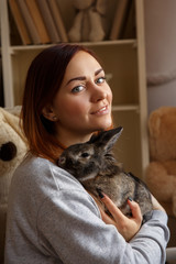 Happy woman holding Easter bunny and smiling to camera at home at Easter day