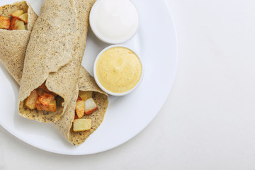 Vegetarian masala dosa with potato, chutney and sambar sauces.