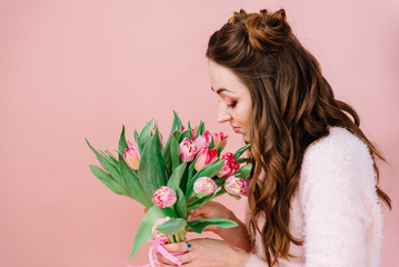 A girl in a pink room with a bouquet of tulips in her hands