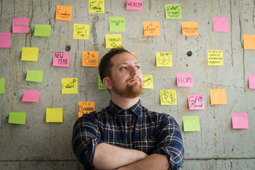 Happy man crossed arm with sticky notes chart on cement wall.  Entrepreneur concept.
