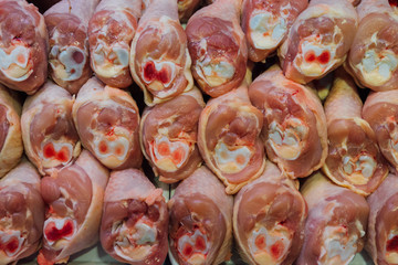 Multiple chicken legs on tray in a market