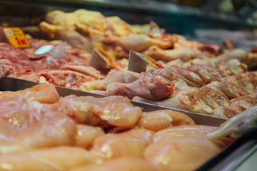 Multiple chicken legs on tray in a market