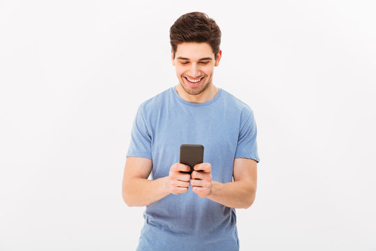 Attractive man with short dark hair chatting or typing text message using cell phone, isolated over white background