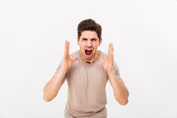 Fototapeta premium Photo of aggressive or irritated man screaming on camera while lifting hands to face, isolated over white background