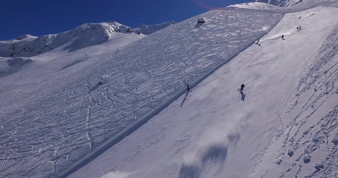 Skiers rush down the slopes of a famed ski resort in of Andermatt. Long shot.