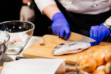 Woman cook preparing and cleaning raw dorada fish