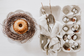 Natural Easter table decoration with silverware and cup cake in a wreath on wooden table