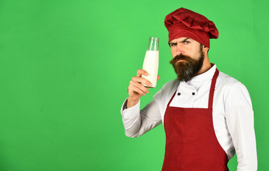 Man with beard holds glass bottle on green background