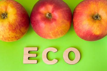 Apple Eco product or food. Three apples are on green background with text eco wooden letters. Example of sustainable environmentally or ecological friendly product, Eco innovation or green marketing