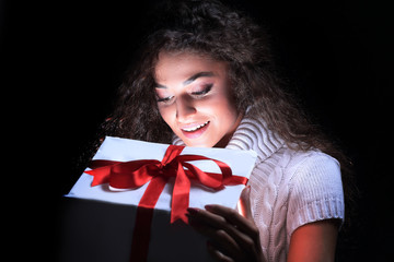 Portrait of a beautiful young brunette peering in a gift box