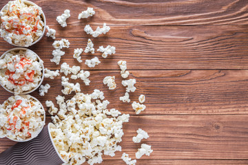 Popcorn in paper cups on a rustic wooden background with copy space, top view, flat lay. Cinema concept. Sweet popcorn with strawberry syrup.