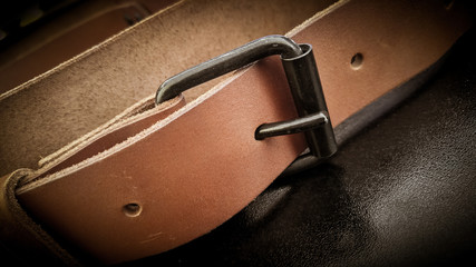 A beautiful brown hand made leather camera sling strap on a black background. Photographer equipment, stylish, vintage, retro feel.