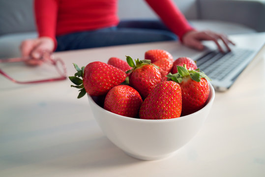 frische Erdbeeren am Arbeitsplatz mit Frau am Computer
