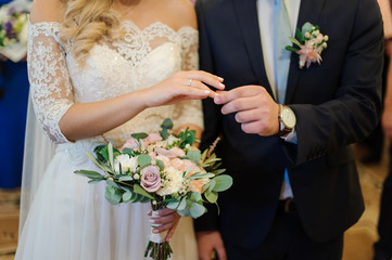 Bridegroom putting a wedding ring on the bride finger