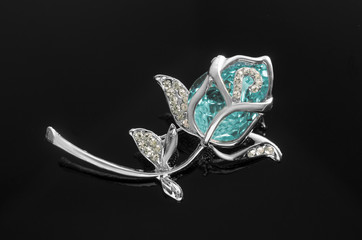 silver brooch rose flower with blue stone isolated on black