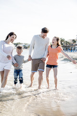 Familie beim Strandspaziergang im Urlaub 