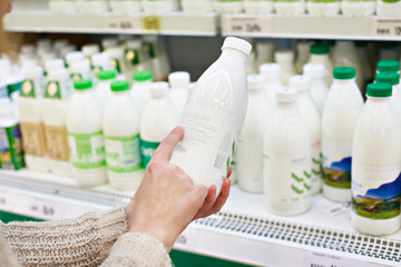 Woman chooses milk and dairy products at store