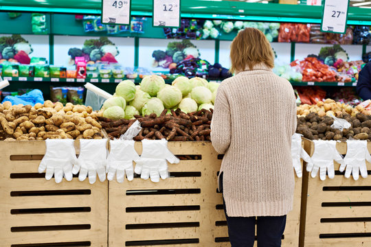 Woman selects vegetables at grocery store