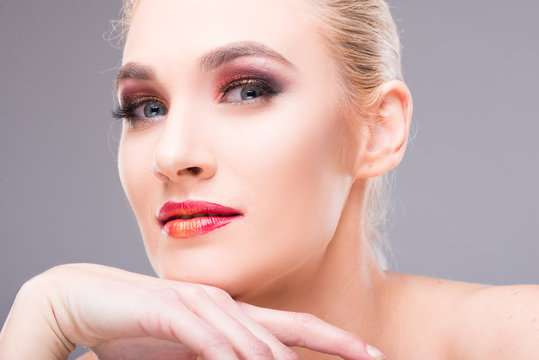 Model posing with hand on chin wearing professional make-up.