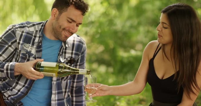 4K Happy romantic couple on summer picnic with young man pouring wine