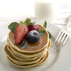 American pancakes with berries on a light background.