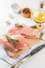 Raw meat, chicken breast filet, with olive oil, herbs and spices on white marble background, copy space