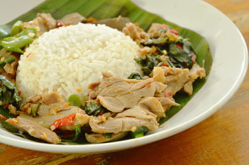 spicy fried duck meat with basil leaf and rice on fresh banana leaf