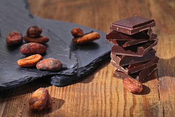 Broken dark chocolate, cocoa powder and coffee beans on a wooden table