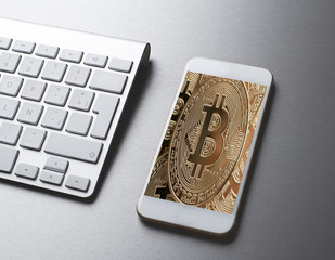 Smartphone with Bitcoin concept on the screen next to keyboard on gray background. Business Concept