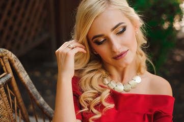 Naklejka premium Fashionable attractive blonde woman in red dress sitting on chair.