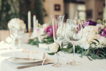 Wedding table served and decorated with flowers and candles, close up on whine glasses 