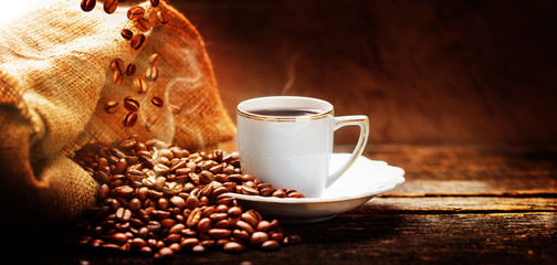 Coffee cup with jute sack of roasted beans - obrazy, fototapety, plakaty