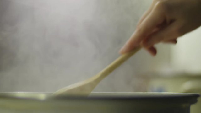 Hand stirring in a cooking pot