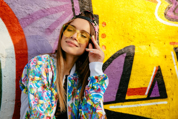 Charming pretty girl in eyeglasses, closed her eyes, enjoying leisure, standing near the wall with...