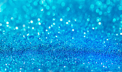 Blue defocused glitter background with copy space. Holiday texture. Wallpaper. Glitter light spots on blue background, defocused